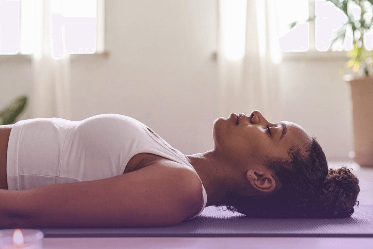 Woman resting peacefully in a relaxation pose, representing holistic stress relief and hormone balance through gut health practices.