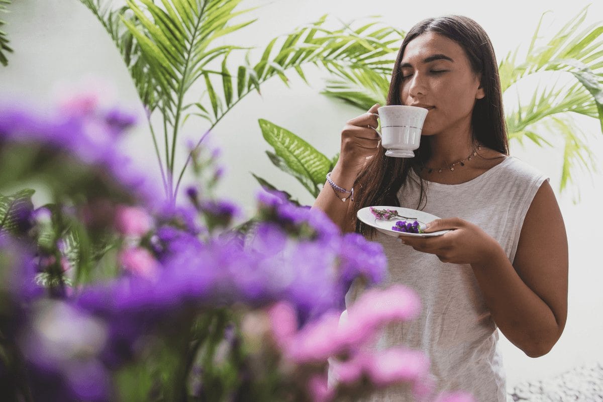 Woman enjoying a calming herbal tea in a natural setting, symbolizing stress relief and gut-brain balance.