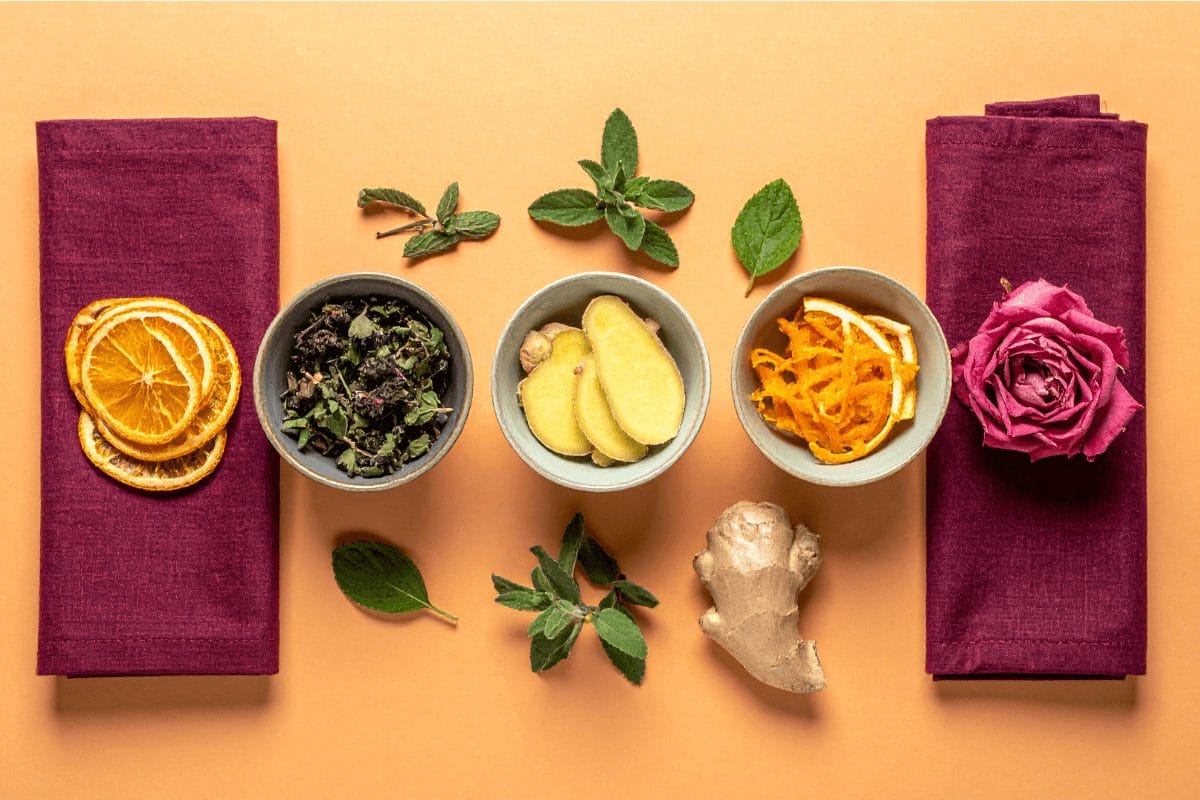 Herbal alchemy for healing – everyday Ayurvedic herbs like ginger, mint, and rose on saffron and burgundy background, symbolizing clarity and balance.